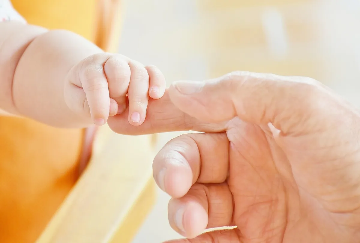 Newborn's hand holding an adult's finger