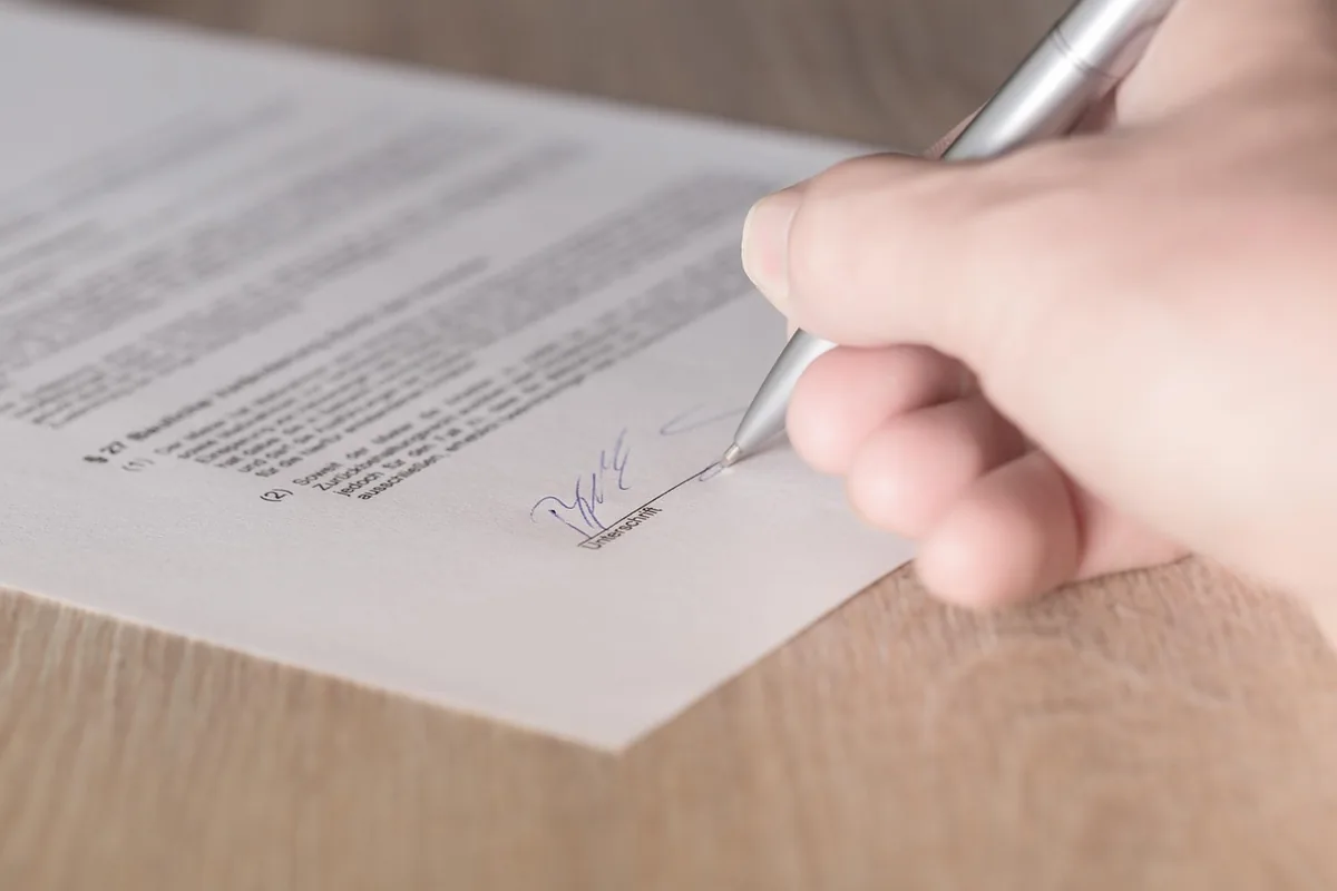 Hand signing an agreement with a pen
