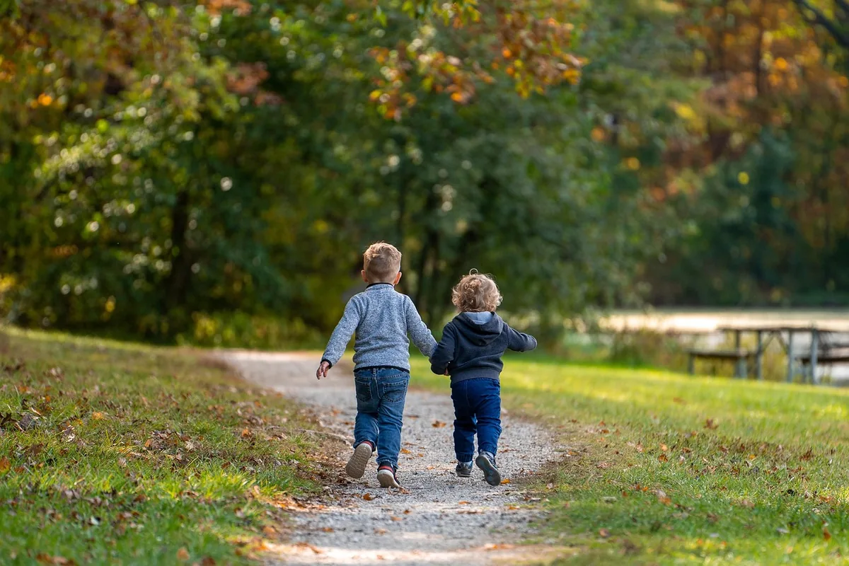 Two toddlers walking along a park path